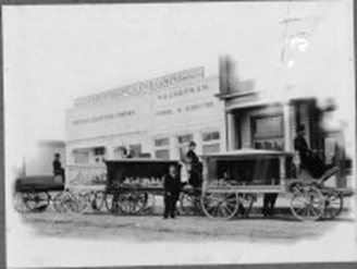 A trio of wagons waits on a street in front of an old building